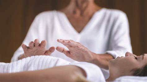 A Reiki practitioner channeling energy with hands held gently over a reclining client